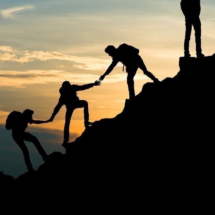 Nhóm người hỗ trợ nhau leo núi lúc hoàng hôn, minh họa sức mạnh của việc kết nối với những người tích cực để vượt qua cô đơn